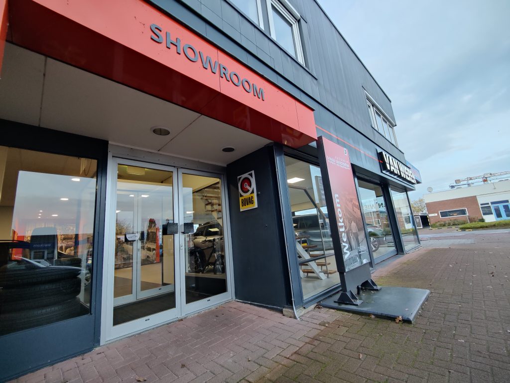 De gevel van Autohuis van Wieren aan de Industrieweg 3 in Meppel met de oranje luifel SHOWROOM en het welkomstbord