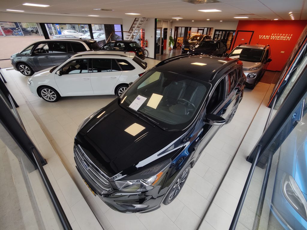 De showroom van boven gezien met een zwarte Ford Kuga en de oranje wand met het logo